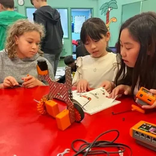 Three students building a robot together at the workbench