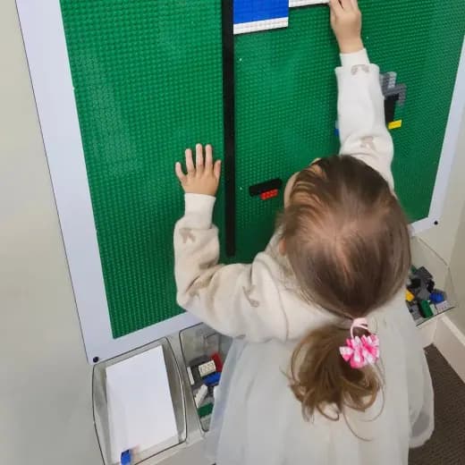 A preschooler building a LEGO flag on the classroom brick wall