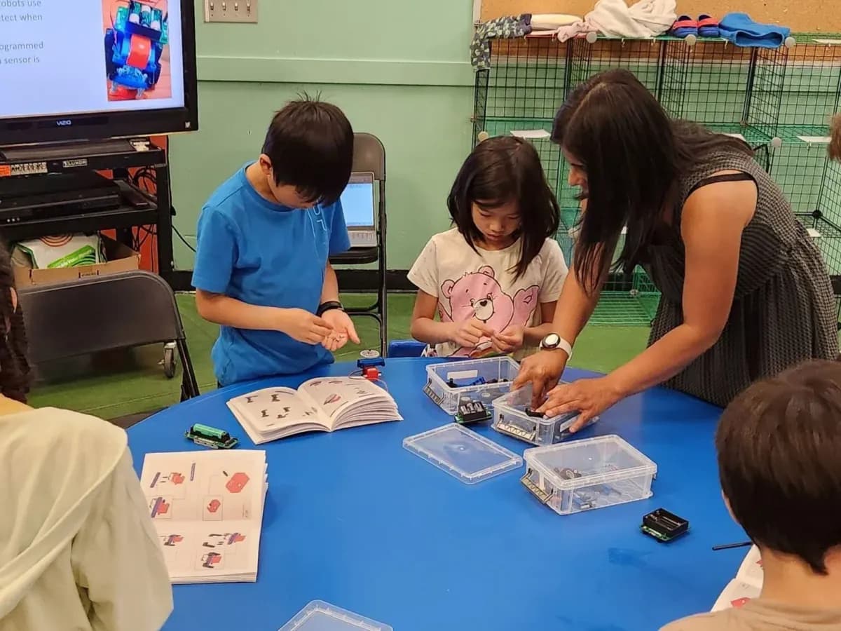 An older student helping a younger one with their build