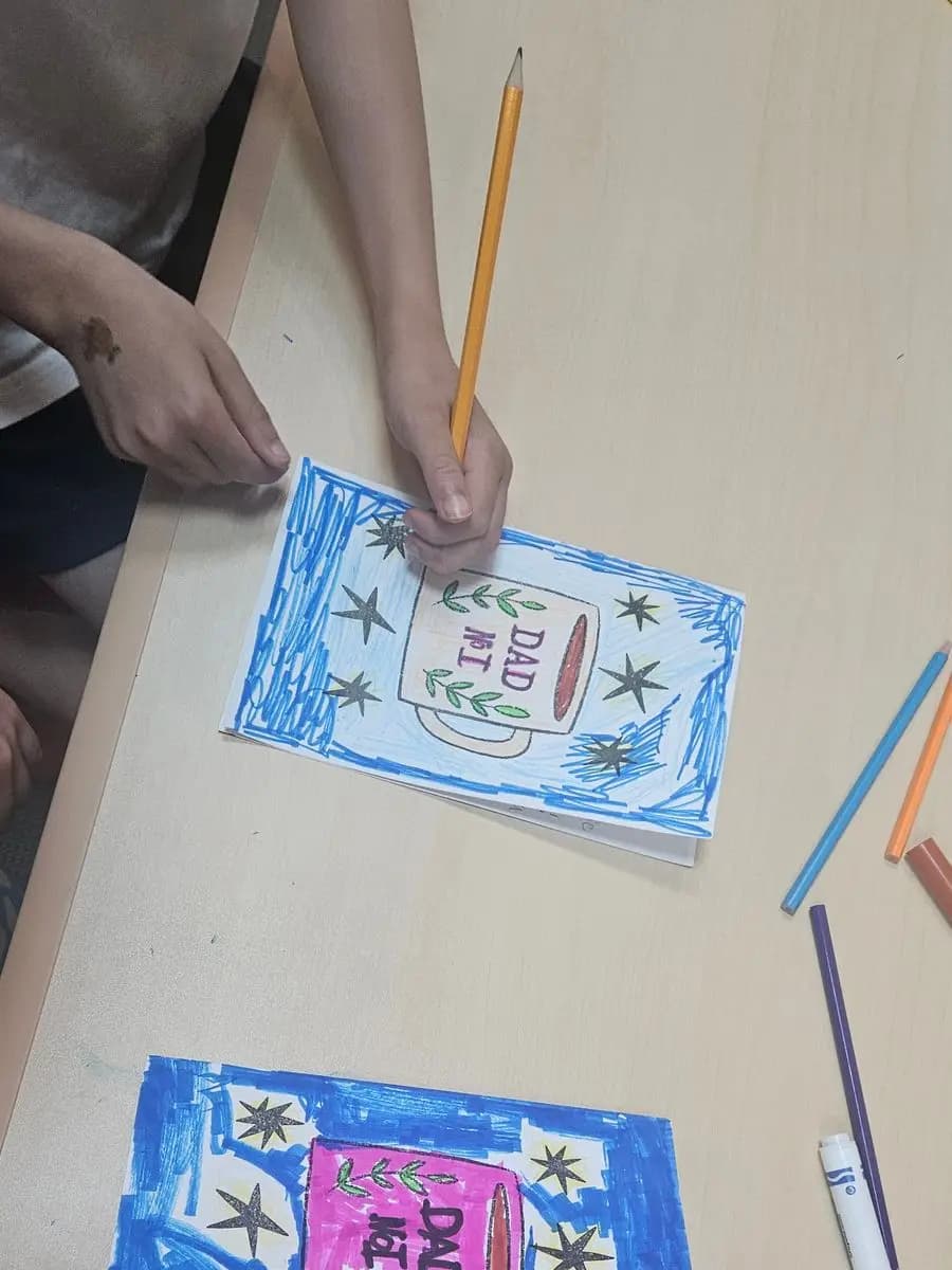 A student colouring a hand-made card at the craft table